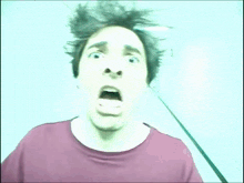 a man in a red shirt is making a funny face with his hair blowing in the wind