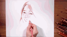 a person is drawing a woman 's face on a piece of paper with colored pencils on the table