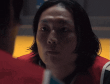 a man with long hair is looking at another man