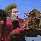 a man in a pink suit with green hair is holding a piece of aluminum foil
