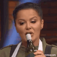 a woman is drinking wine from a bottle with her mouth .