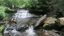 a man standing on a rock near a waterfall