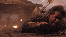 a man is laying on the ground with a bloody face and an arrow in his back