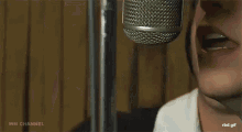a man is singing into a microphone in a recording studio with his eyes closed .