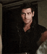 a man with a beard is wearing a black jacket and looking at the camera .