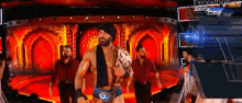 a man in a wrestling outfit is walking on a stage holding a championship belt .