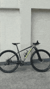 a black and yellow bicycle is parked in front of a wall