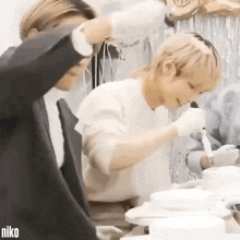 two men are standing next to each other in a kitchen .