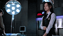 a woman in a uniform stands in an operating room next to a man