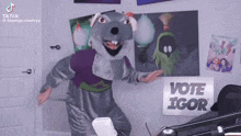 a man in a chuck e cheese costume is dancing in front of a sign that says vote igor