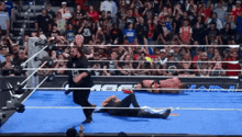 a wrestler is laying on the ground in a ring with a crowd watching