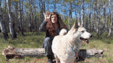 a man and a dog are sitting on a log in the woods ..