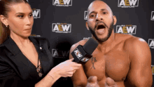 a shirtless wrestler is being interviewed by a woman in front of a wall that says aew