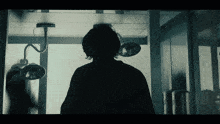 a silhouette of a person in an operating room with lights hanging from the ceiling