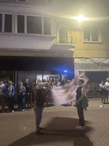 a group of people are gathered outside of a building that says ' alois ' on it