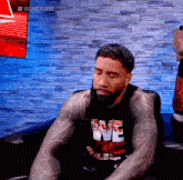 a man with a beard is sitting on a couch with his eyes closed and wearing a we shirt .