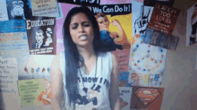 a woman stands in front of a wall with posters on it including one that says we can do it