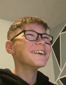 a young boy wearing glasses is smiling and looking at the camera .