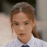 a close up of a woman 's face wearing a white shirt and a blue tie .