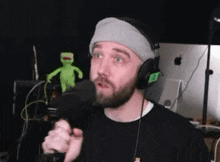 a man with a beard is singing into a microphone while wearing headphones and a headband .