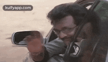 a man is sitting in a car taking a picture of himself in the mirror .