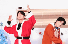 two men in santa claus costumes are dancing in a room .