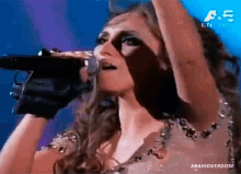 a woman singing into a microphone in front of a screen that says a5 en vivo