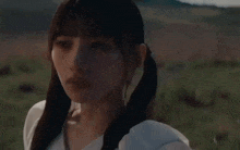a woman with pigtails is standing in a field with mountains in the background