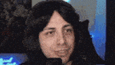 a man wearing a wig and headphones is sitting in front of a microphone and smiling .