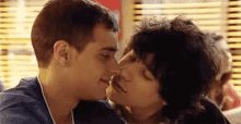 two men are kissing each other in front of a window in a restaurant .