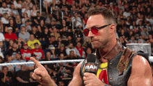 a man in a wrestling ring holds a microphone with the word raw on it
