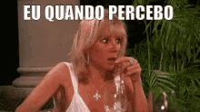 a woman sitting at a table with a glass of wine and a caption that says eu quando percebo .