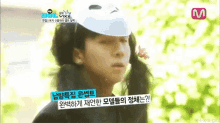 a person wearing a white hat and pigtails is standing in front of a tree .