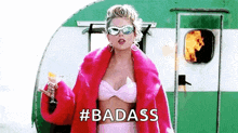 a woman wearing a pink fur coat and sunglasses is holding a glass of wine .