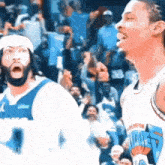 two basketball players are standing in front of a crowd .
