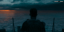 a man stands on a boat looking at the ocean and the words pranay varma on the bottom right