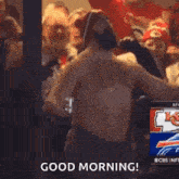 a shirtless man is standing in front of a crowd of people and a sign that says `` good morning '' .