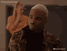 a man in a camo jacket stands in front of a woman in a yellow dress with the words step up series on the bottom right