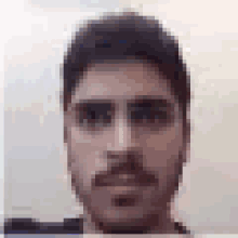 a close up of a man 's face with a beard and glasses .