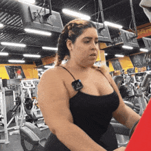 a woman in a black tank top rides an exercise bike