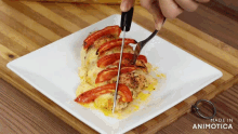 a person is cutting a piece of chicken with tomatoes on it