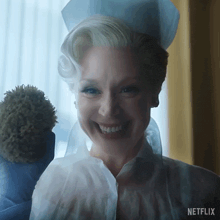 a woman in a nurse 's uniform is smiling and holding a stuffed animal with netflix written on the bottom