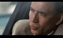 a man is sitting in the back seat of a car with his eyes closed .