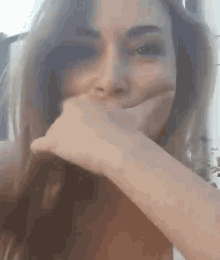 a close up of a woman covering her mouth with her hand .