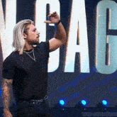 a man with long blonde hair and a beard is standing in front of a large sign that says ' vegas ' .