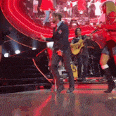 a man in a suit is dancing on a stage with a guitar player