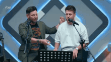 two men singing in front of microphones with rtve written on the bottom right