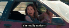 a woman is sitting in the driver 's seat of a car and says `` i 'm totally topless ! ''