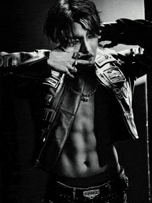 a black and white photo of a man wearing a leather jacket and a belt that says dsquared2 on it