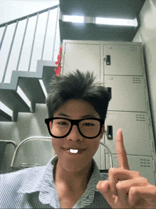 a young man wearing glasses and a striped shirt is giving the middle finger
